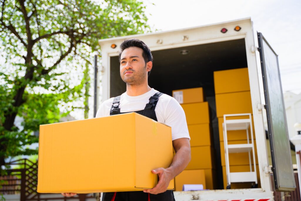 Happy delivery man holding box in front of delivery truck, Delivery man checking order of moving